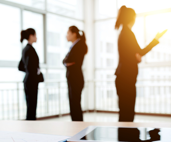 Women in discussion in office with glass exterior walls with the sun beaming